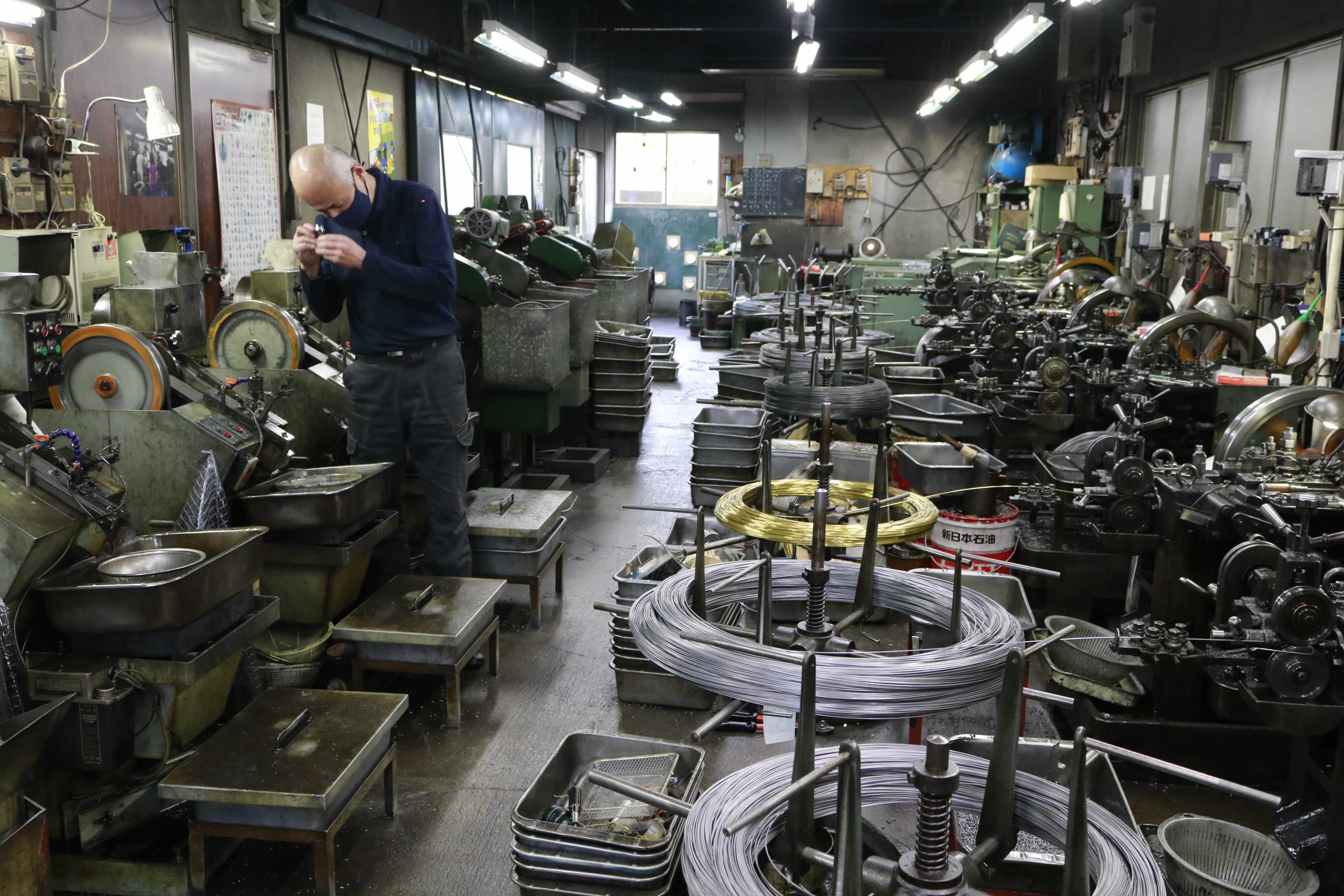 ワイヤー状の材料から圧造機(右列)と転造機(左列)がリズムよくねじを大量生産していく(浅井製作所)